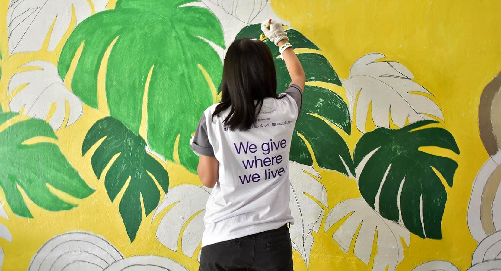 A team of people smiling and holding up their hands while holding paintbrushes